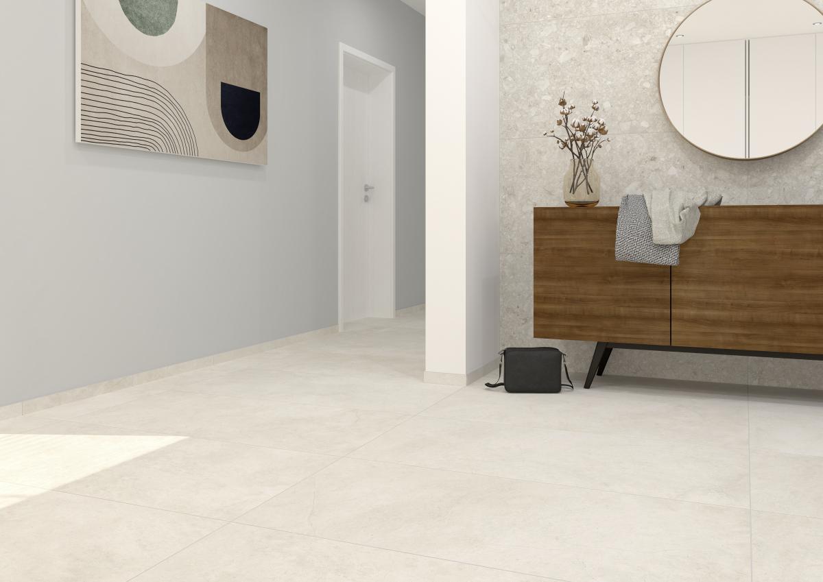 Ein modern gestalteter, heller Flur- und Eingangsbereich mit großformatigen, beigefarbenen Bodenfliesen, einer hellblauen Wand mit einem abstrakten Kunstwerk und einer gegenüberliegenden Wand in Terrazzo-Optik, vor der ein Sideboard aus dunklem Holz steht.